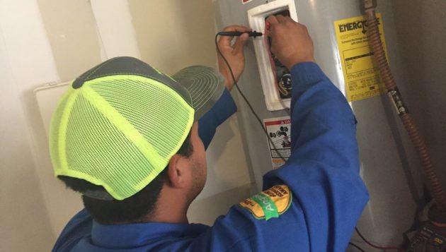 Professional plumber using tools to make adjustments to a water heater