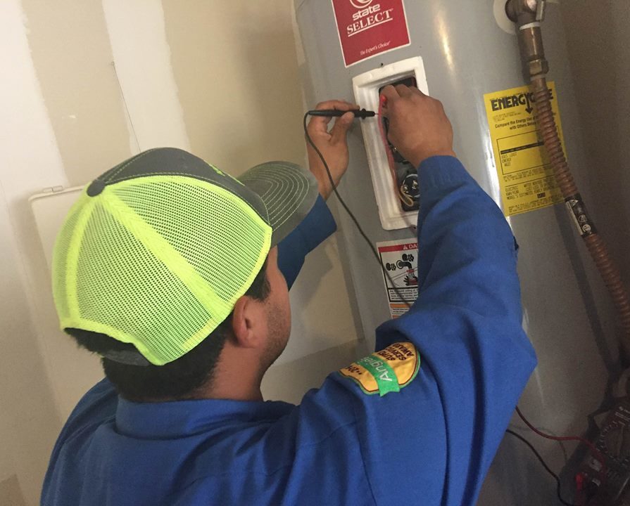 Professional plumber using tools to make adjustments to a water heater