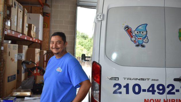 a smiling Mr. Plumber employee standing next to a company vehicle