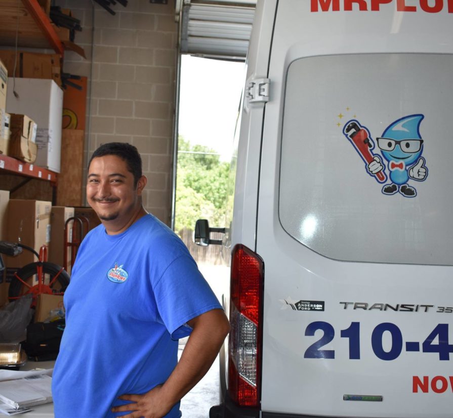 a smiling Mr. Plumber employee standing next to a company vehicle