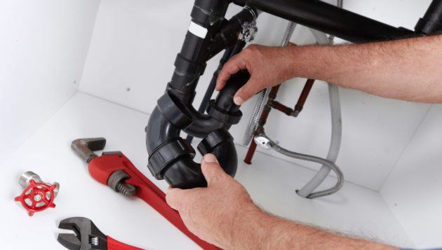 a homeowner making adjustments to the pipes in their plumbing system