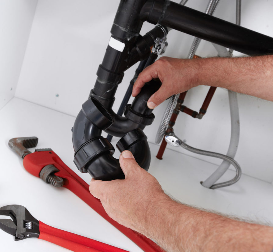 a homeowner making adjustments to the pipes in their plumbing system