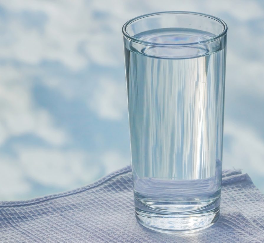 a clear cup of water with the sky in the background