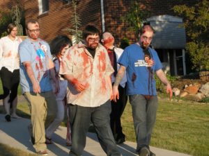 a group of people walking on the sidewalk while dressed like zombies