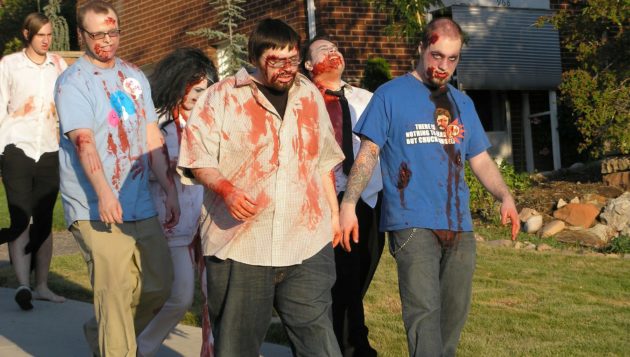 a group of people walking on the sidewalk while dressed like zombies