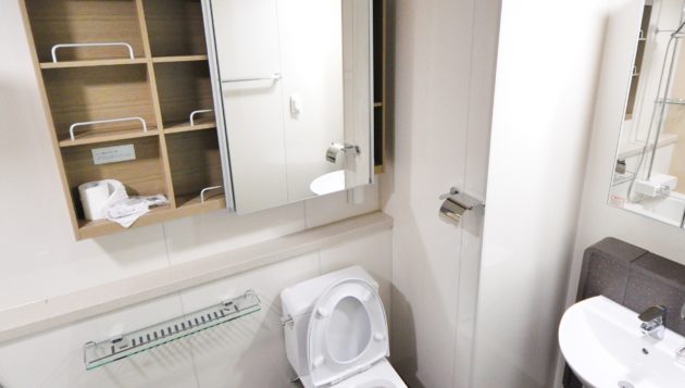 image of a clean bathroom with empty shelves above the toilet