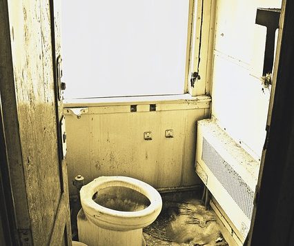 a filthy bathroom with dirty walls and a broken toilet