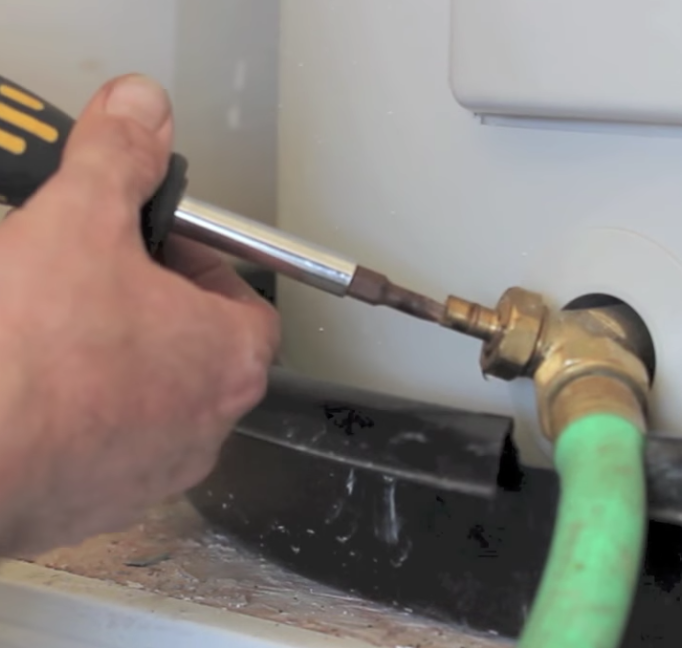 hand using a tool to adjust a part on a water heater