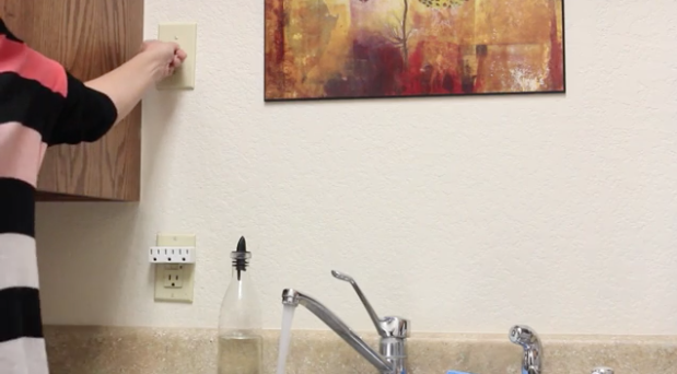 a woman turning the switch on for her kitchen garbage disposal