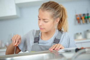 a woman plumber providing repair services for a kitchen sink