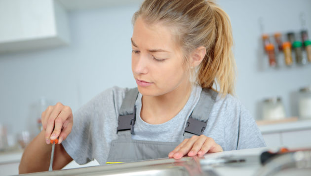 a woman plumber providing repair services for a kitchen sink