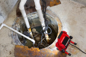 a sump pump in the floor of a San Antonio basement going through plumbing repair services