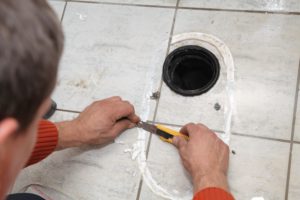 plumber in The Dominion scraping residue off of a tile floor