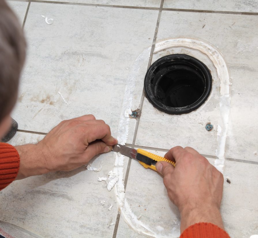 plumber in The Dominion scraping residue off of a tile floor