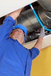 Plumber in Universal City reaching up to adjust a blue pipe