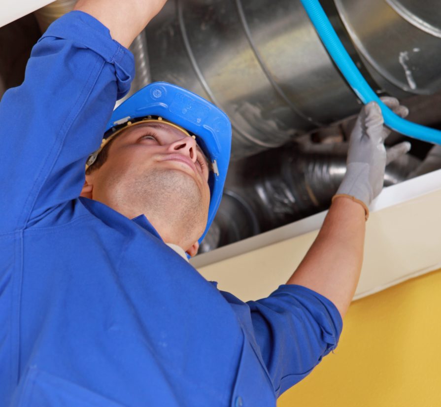 Plumber in Universal City reaching up to adjust a blue pipe