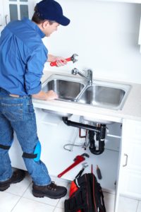 a Leon Valley plumber with a blue hat providing kitchen sink repairs