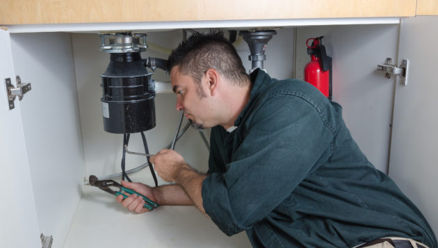 Plumber in Terrell Hills working on a plumbing system inside of a cabinet