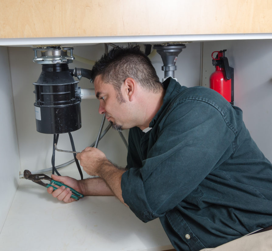 Plumber in Terrell Hills working on a plumbing system inside of a cabinet
