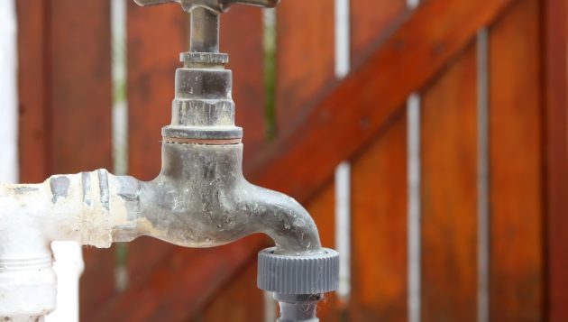 an outdoor water system with a wooden fence in the background