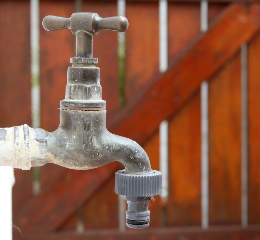 an outdoor water system with a wooden fence in the background