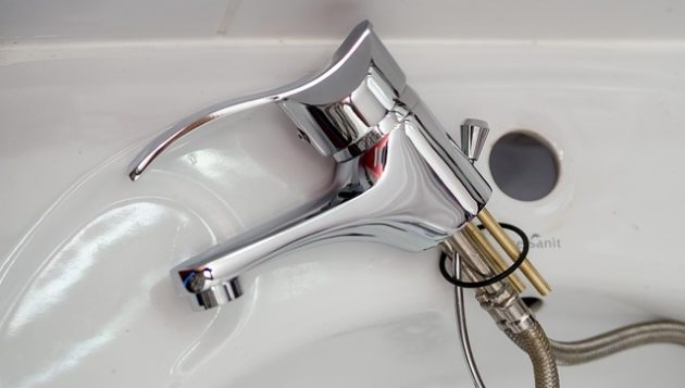 the faucet of a sink pulled out and laying on its side in a converse bathroom