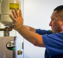 A plumber in San Antonio adjusting a water heater to provide maintenance services