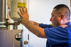professional plumber adjusting a water heater as part of maintenance services