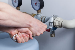 plumber using wrench to provide repair services for the pipes of a water heater