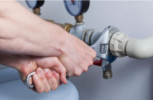 plumber using wrench to provide repair services for the pipes of a water heater