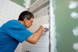 a man performing professional bathroom remodel services for the wall of a shower