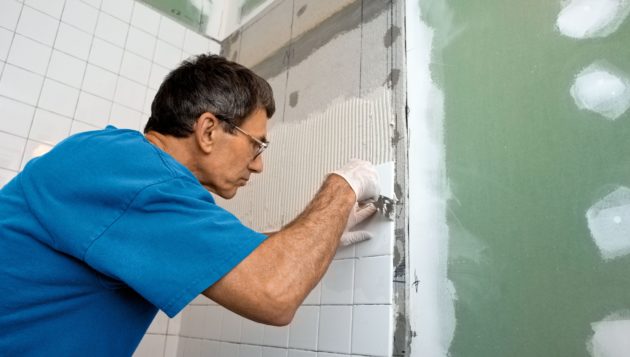 a man performing professional bathroom remodel services for the wall of a shower