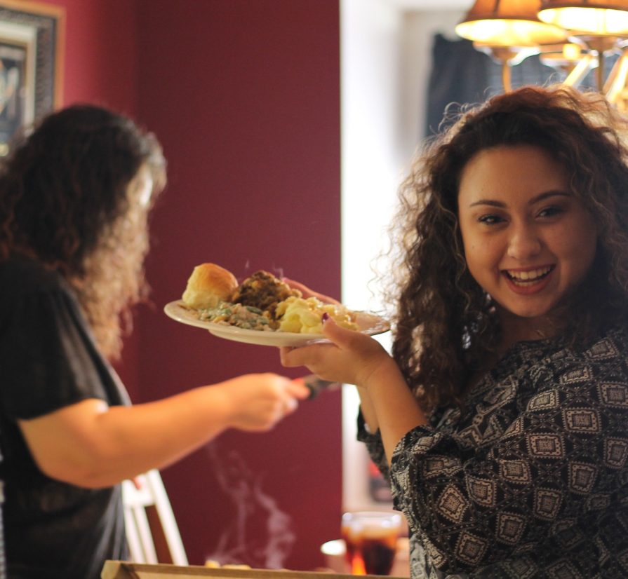 a woman holding a plate of food at a Thanksgiving dinner