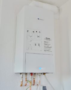 a white tankless water heater installed on a white wall of a San Antonio home