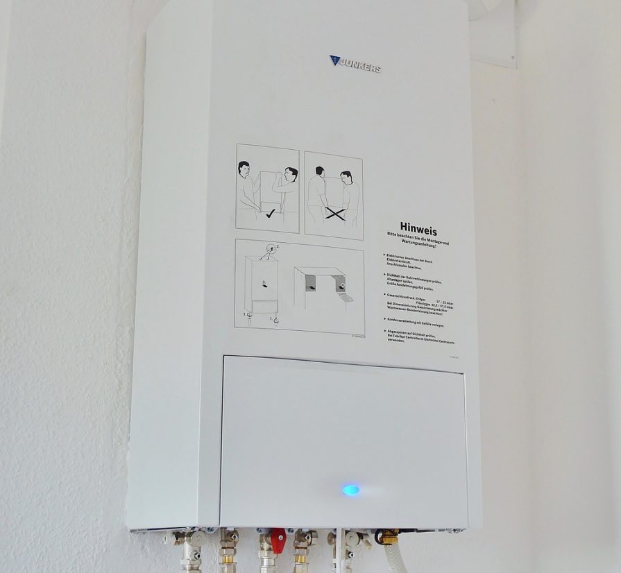 a white tankless water heater installed on a white wall of a San Antonio home