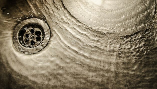 a pool of water attempting to go down a clogged sink drain