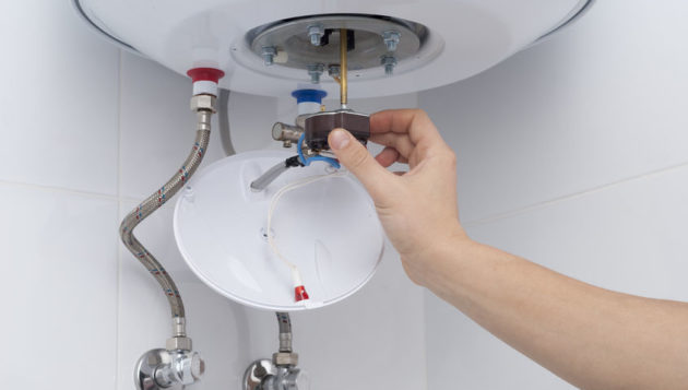 a hand inserting a part into a water heater system