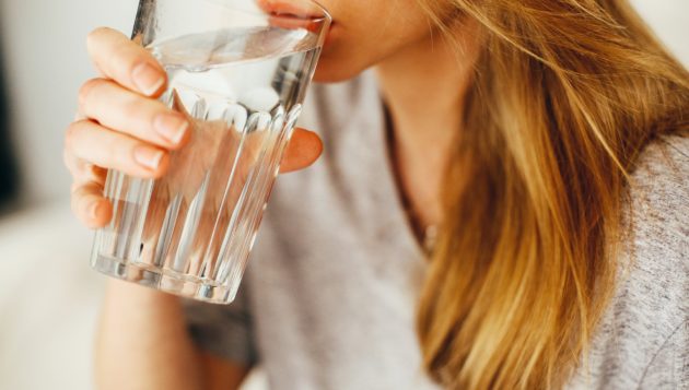 woman drinking water from a clear cup