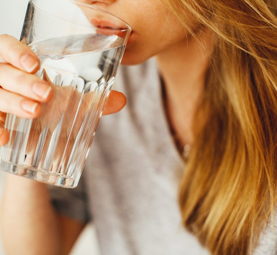 woman drinking water from a clear cup