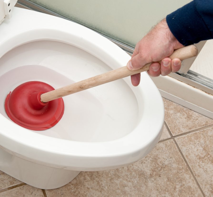 plumber using a plunger to fix a clogged toilet