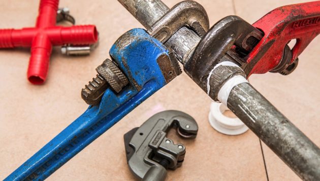 wrenches being used to adjust a plumbing pipe