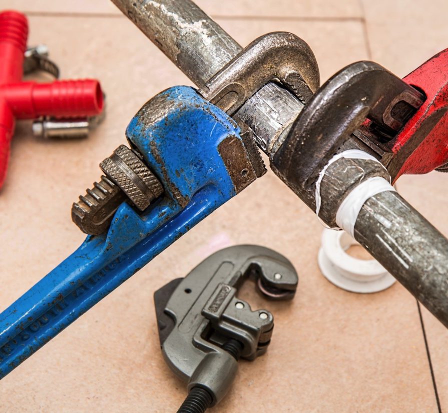 wrenches being used to adjust a plumbing pipe