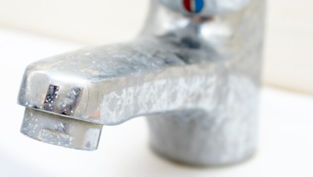 a bathroom sink faucet covered in hard water stains