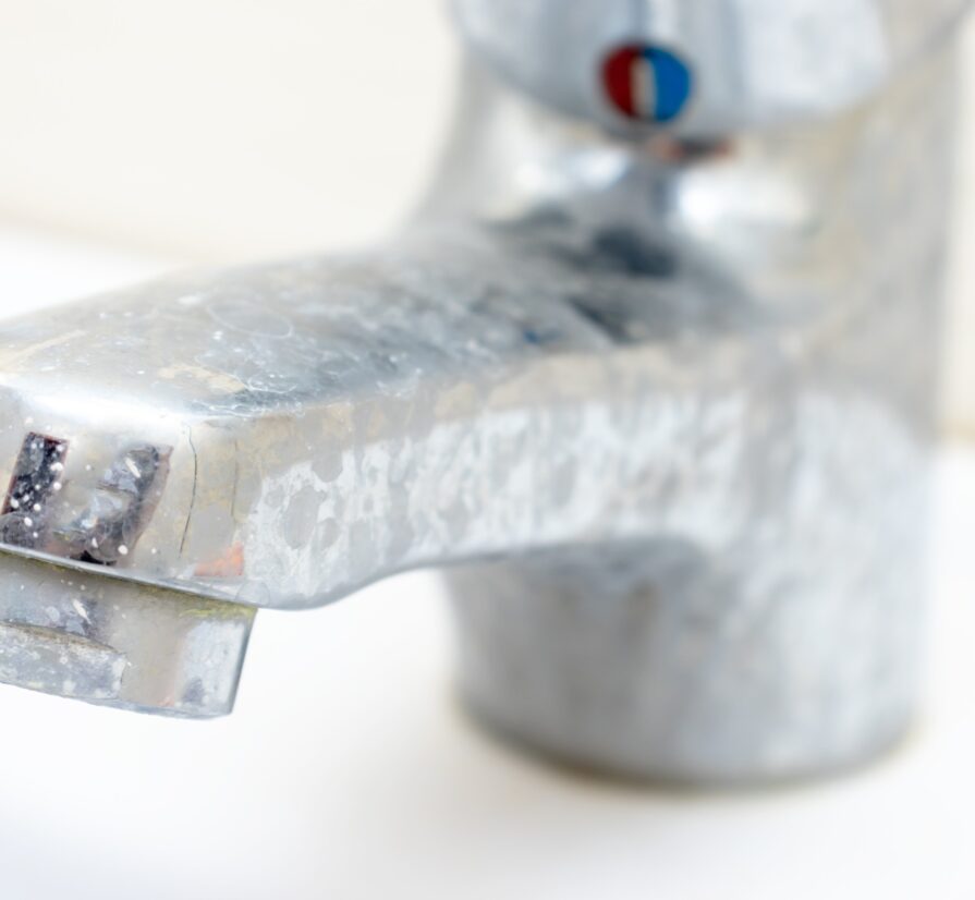 a bathroom sink faucet covered in hard water stains