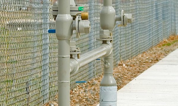 a backflow prevention system next to a fence