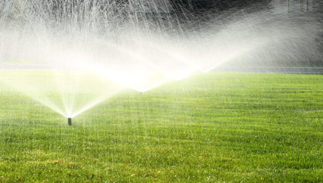 three sprinkler systems watering a yard