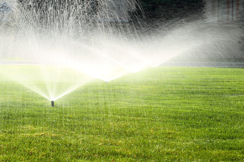three sprinkler systems watering a yard