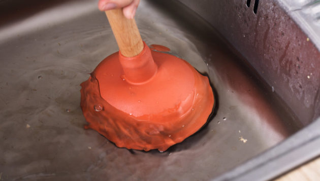 a plunger being used for a kitchen sink clog
