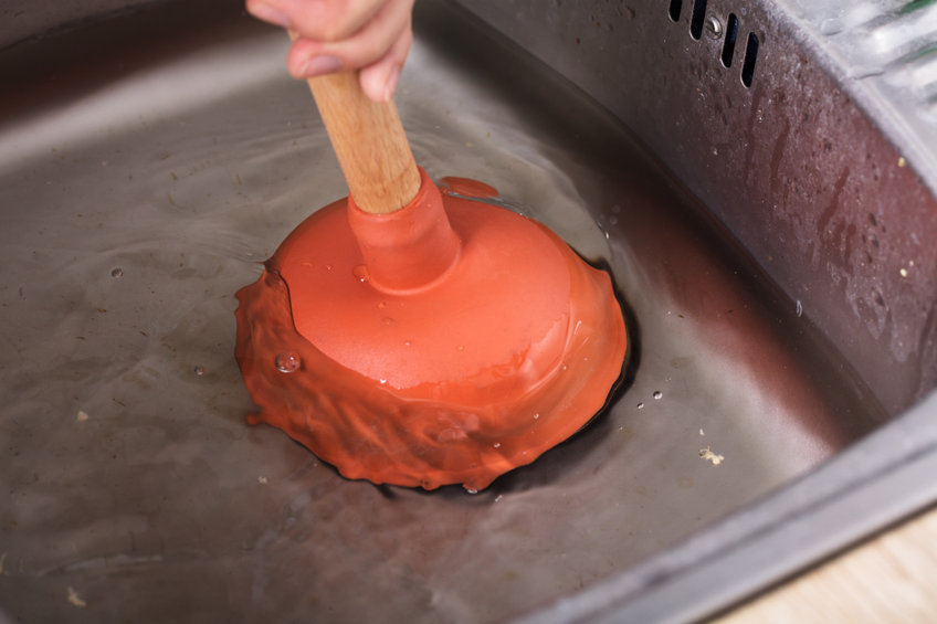 a plunger being used for a kitchen sink clog