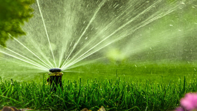 a sprinkler spraying a home's yard with water